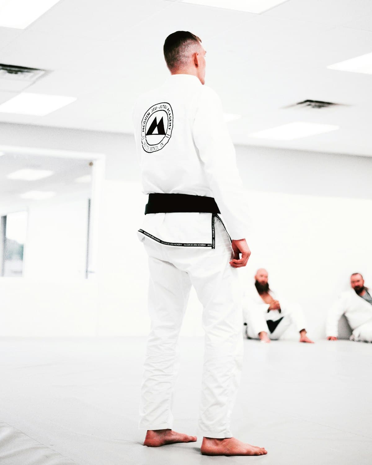 A black belt standing on the mats of a jiu-jitsu academy